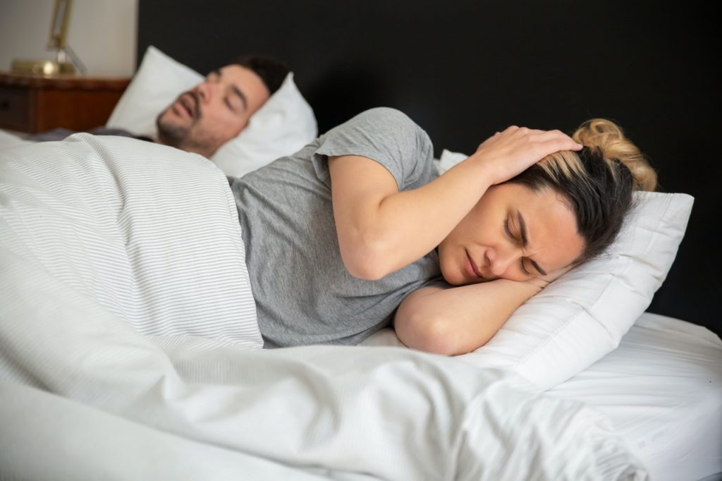 Man snoring while sleep next to woman 